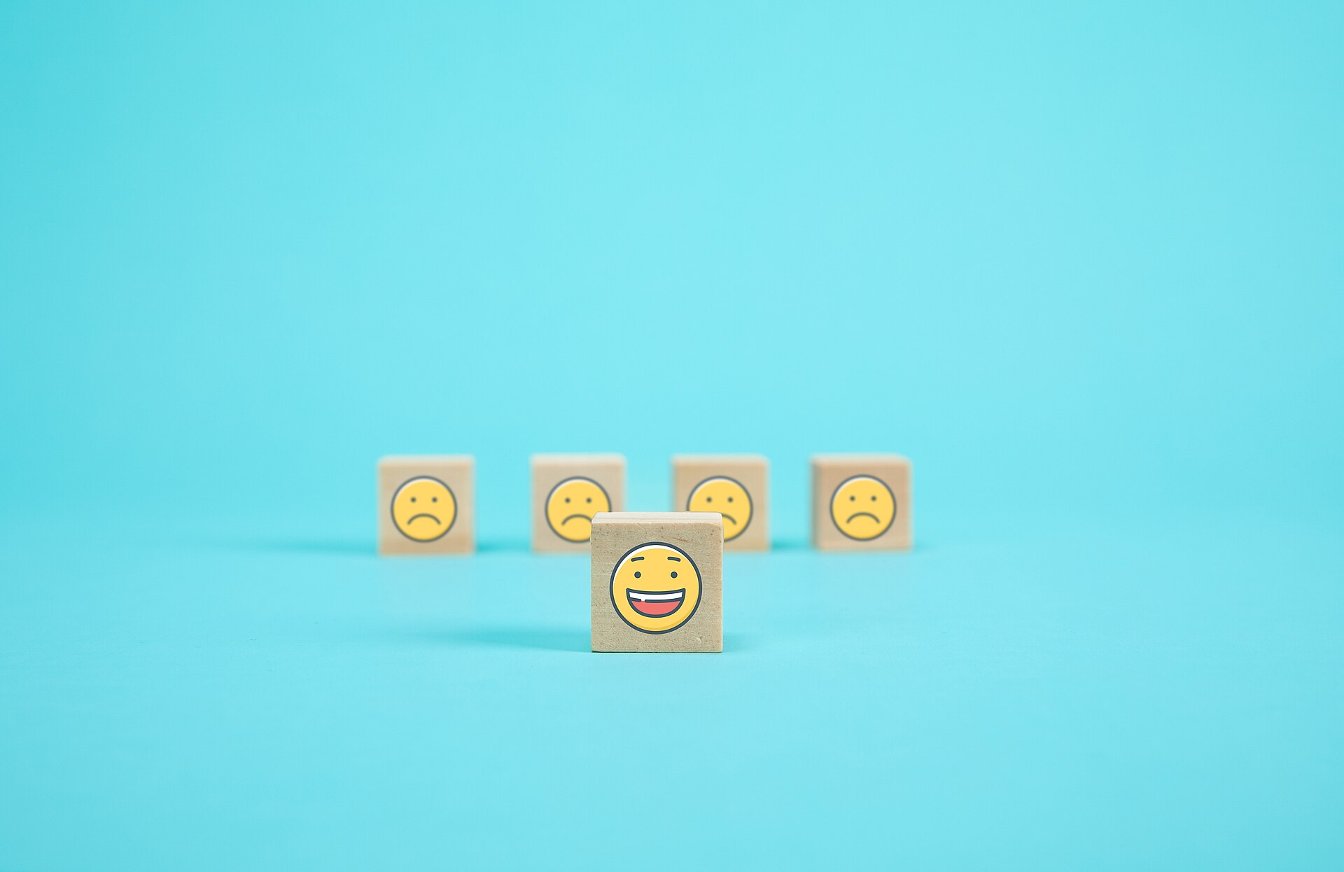 Holzwürfel mit Smiley-Symbolen als Sinnbild für Kundenbewertungen